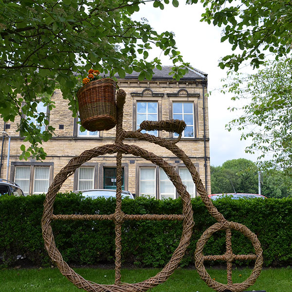 Willow weave penny farthing bike sculpture with bike basket full of planted flowers